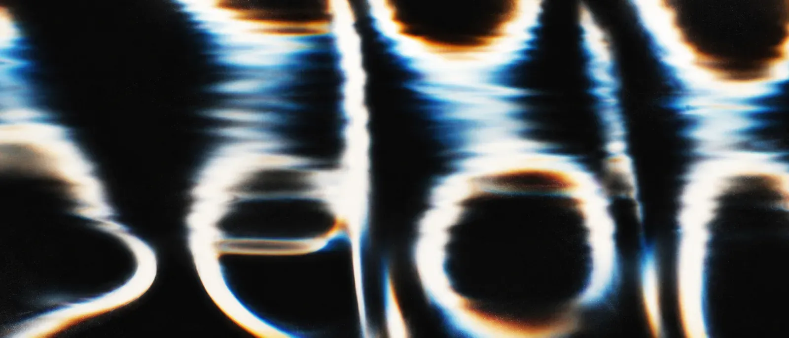 Abstract letterforms made of liquid light, glowing white and amber strokes with blue fringes on black
